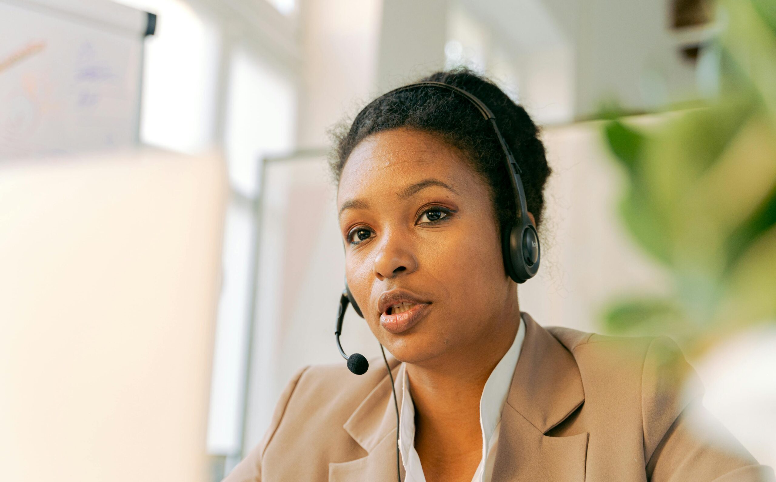 African American woman working in a call center with a headset on, providing customer support.